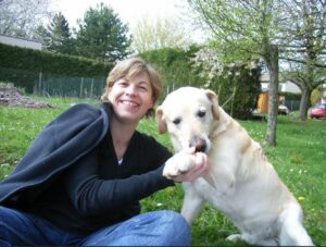 photo d'une femme avec un labrador beige qui lui donne sa patte